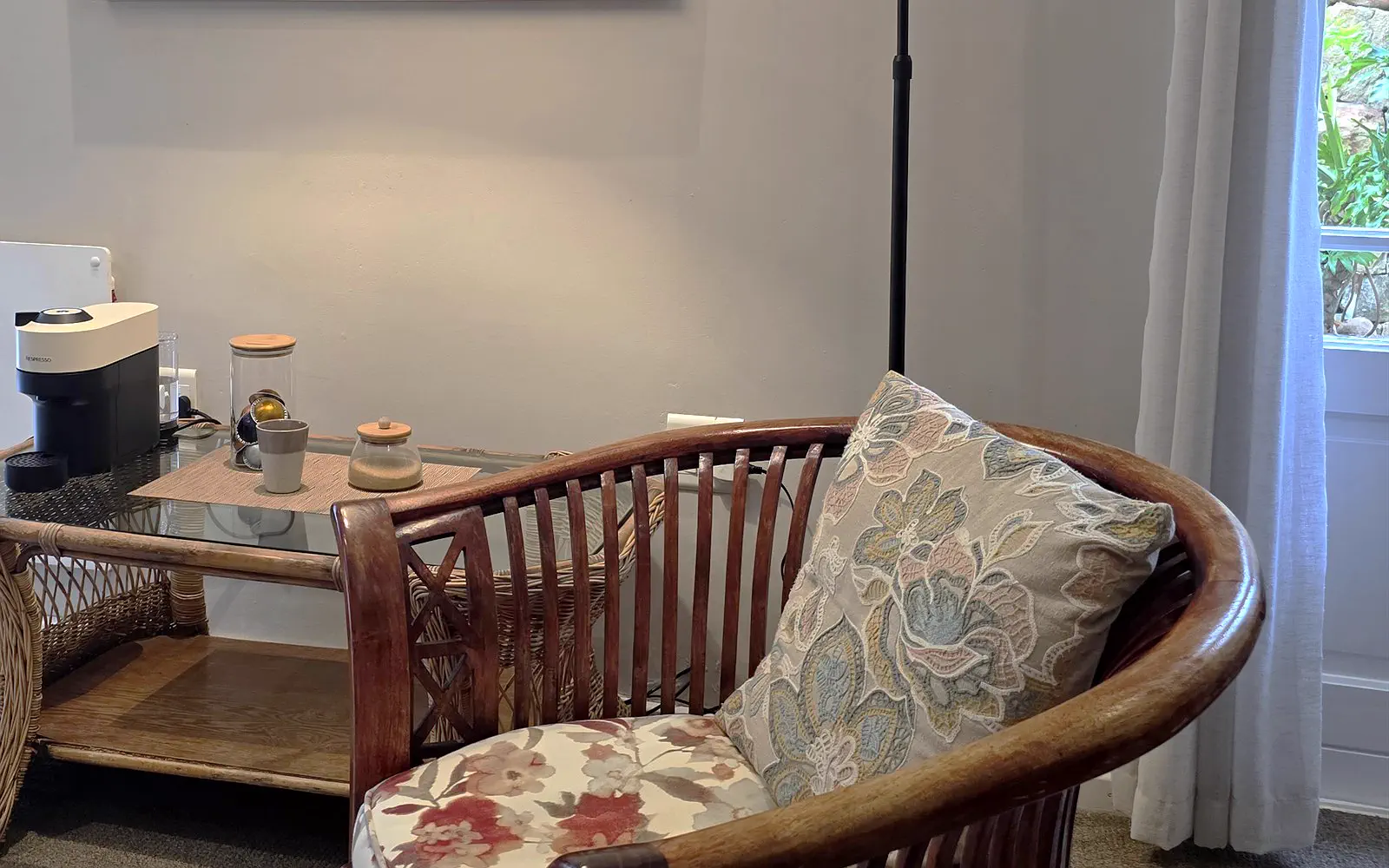 Rattan reading chair with a floral cushion by the window of The Library