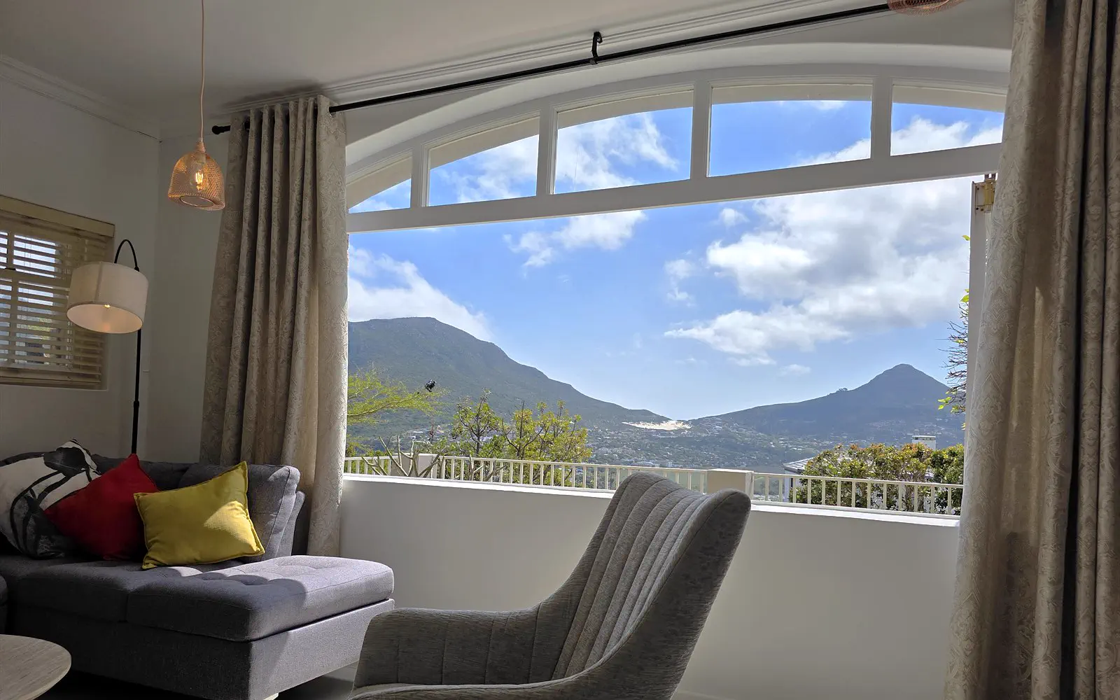 The Lodge living room with an arched window and panoramic views over the mountains and the bay of Hout Bay