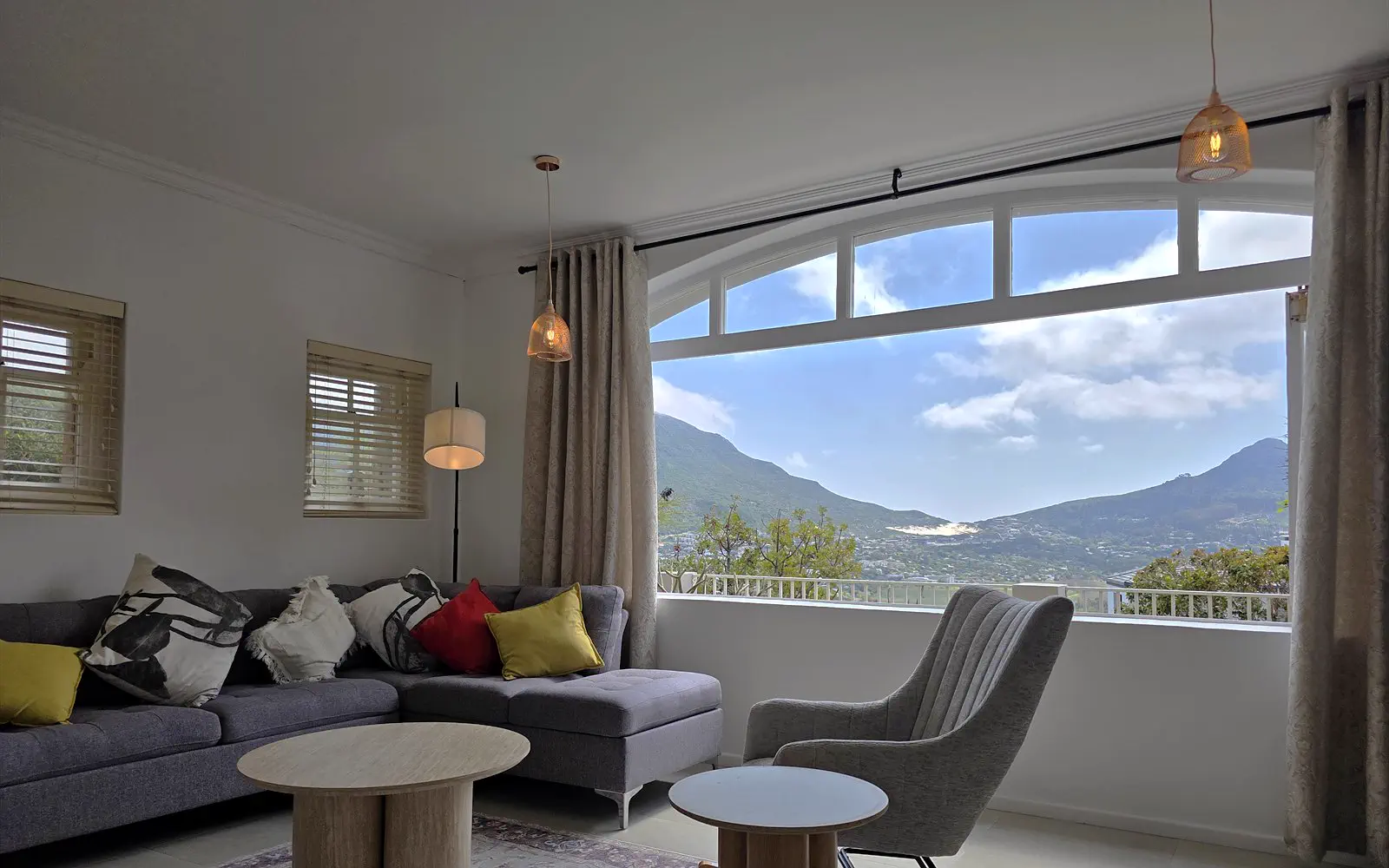 Seating area of The Lodge with corner sofa, armchair and arched window with mountain views