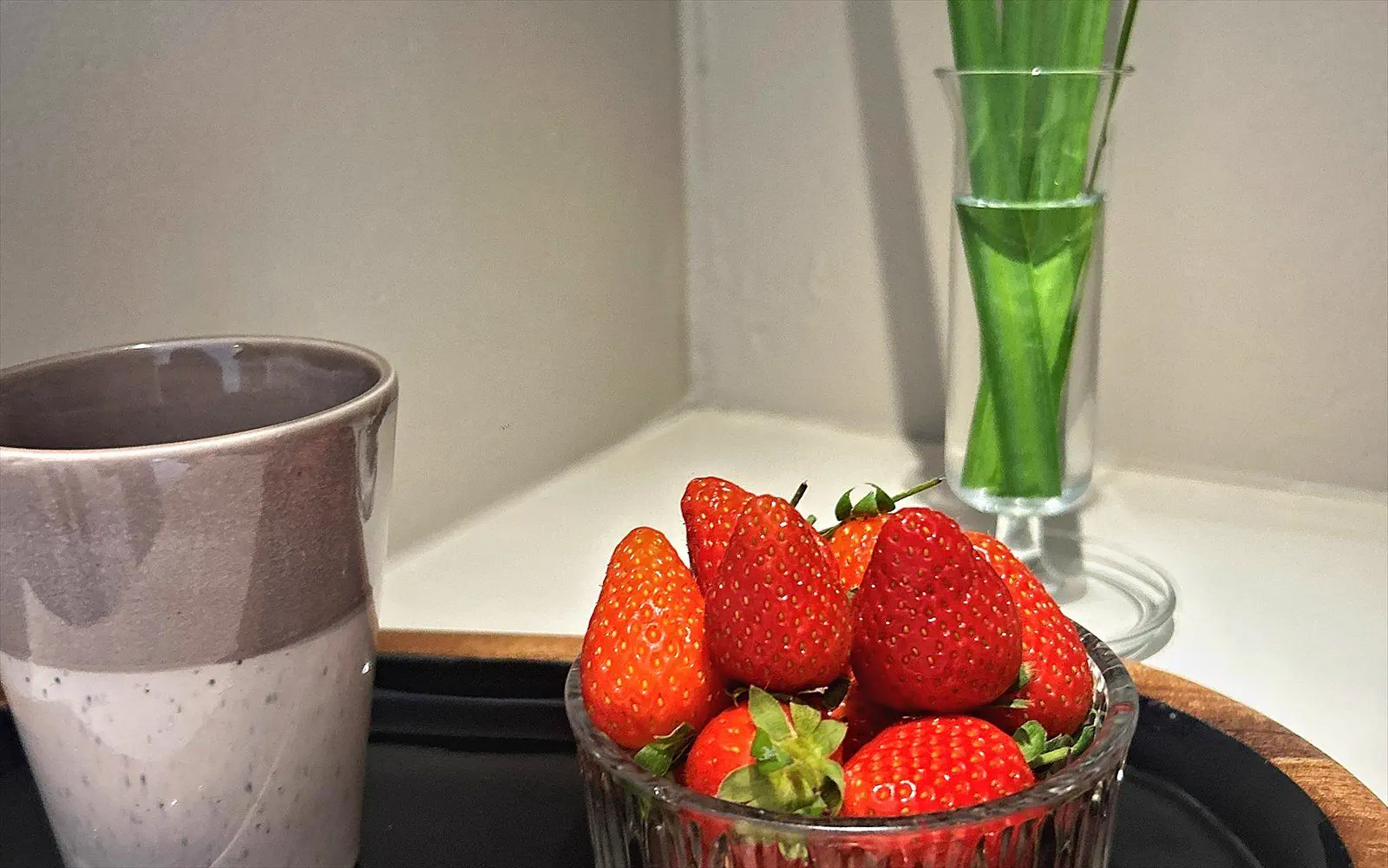 A bowl of fresh strawberries on a wooden tray