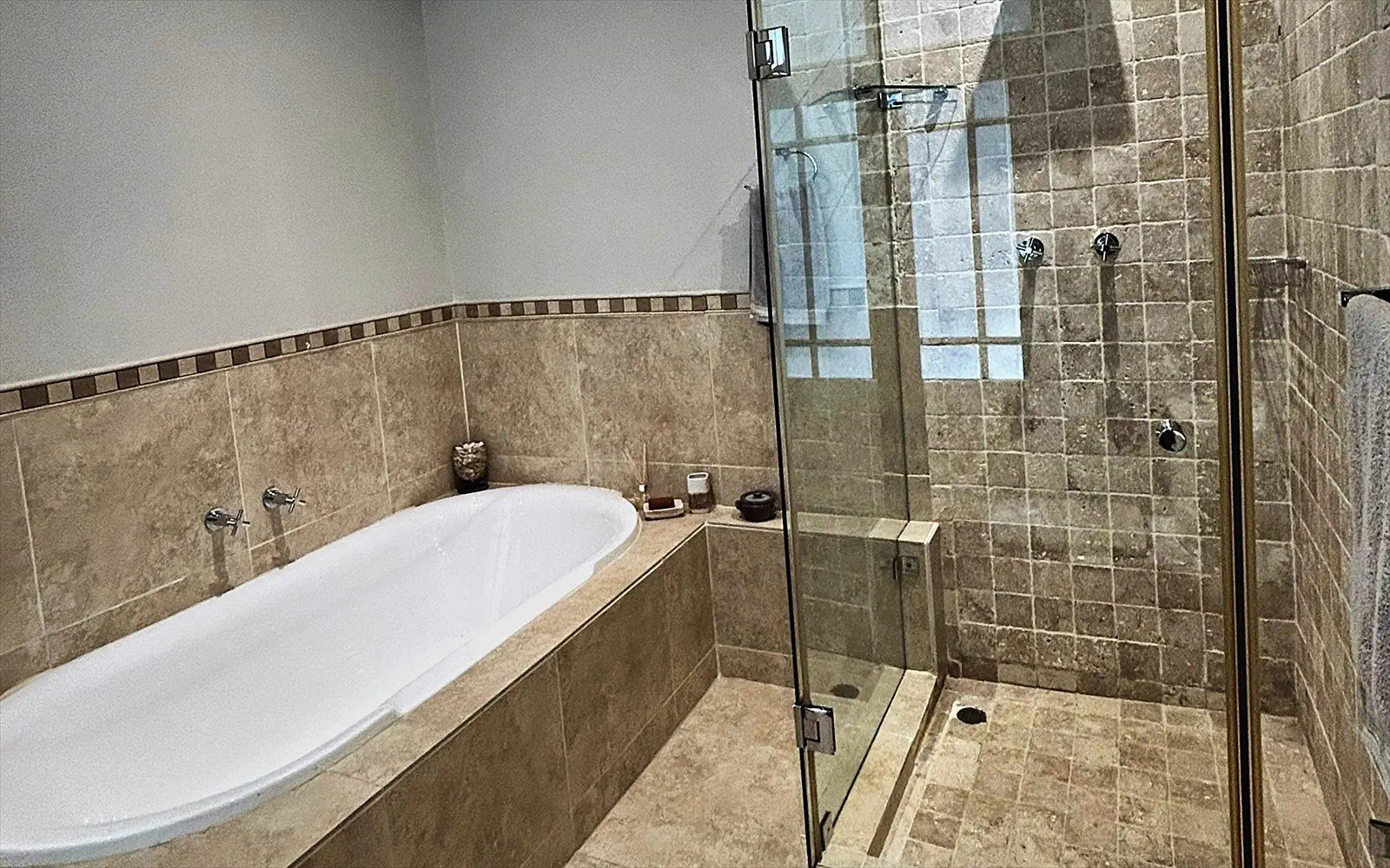 Bathroom with bath and walk-in shower in travertine