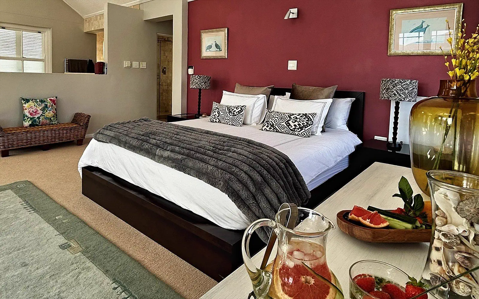 The Penthouse bedroom with a high ceiling, deep red wall and fresh touches on the table