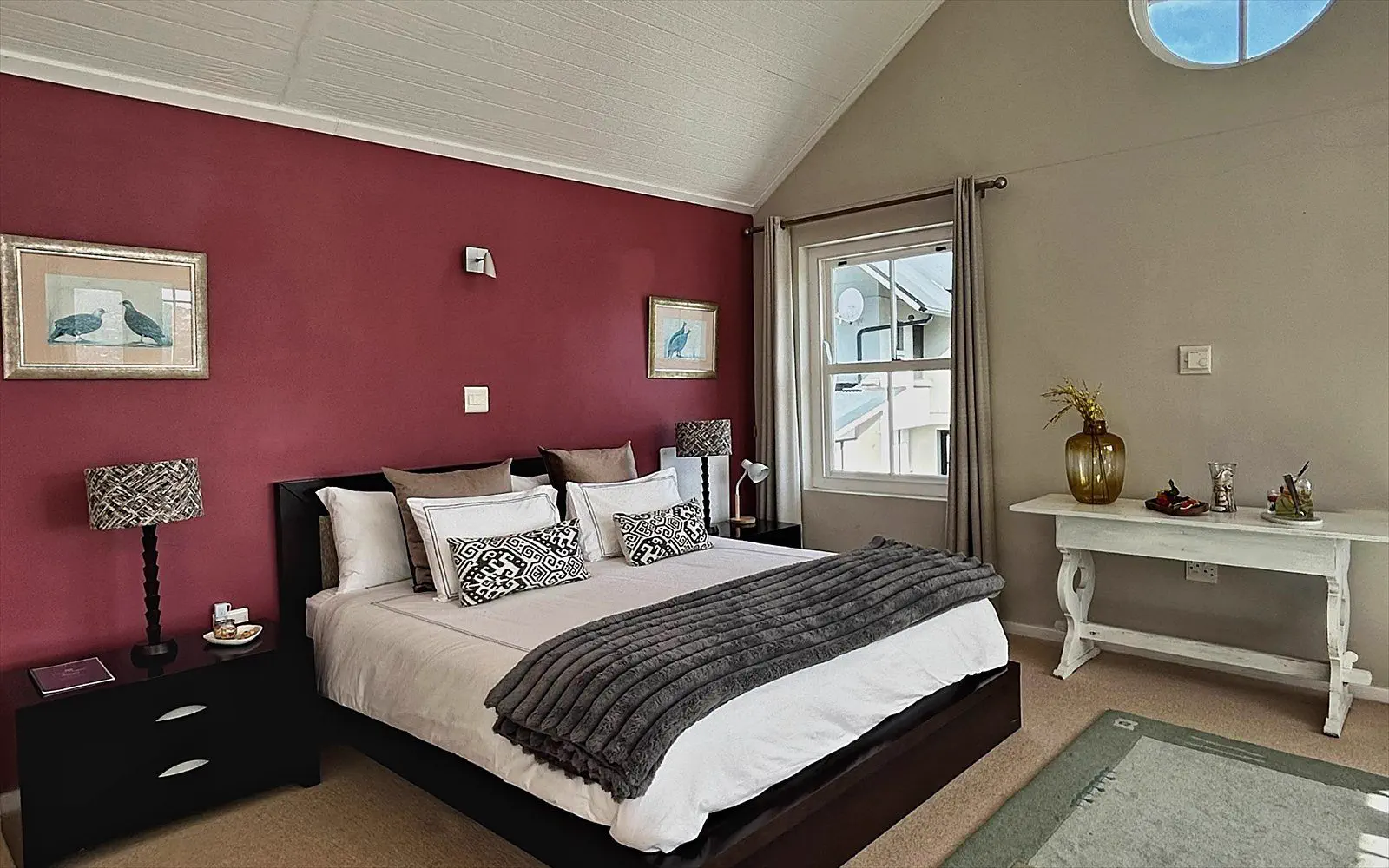 Spacious bedroom with double bed, round window and its own console table