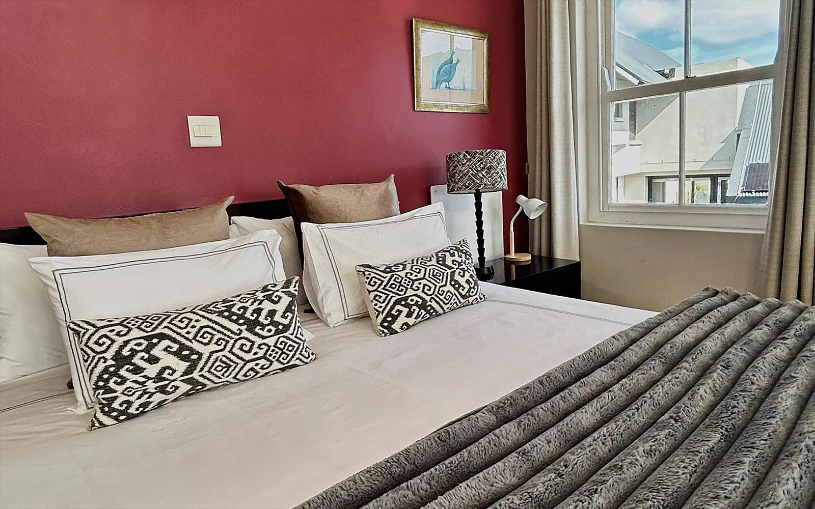 Freshly made bed with crisp linen and daylight through the side window