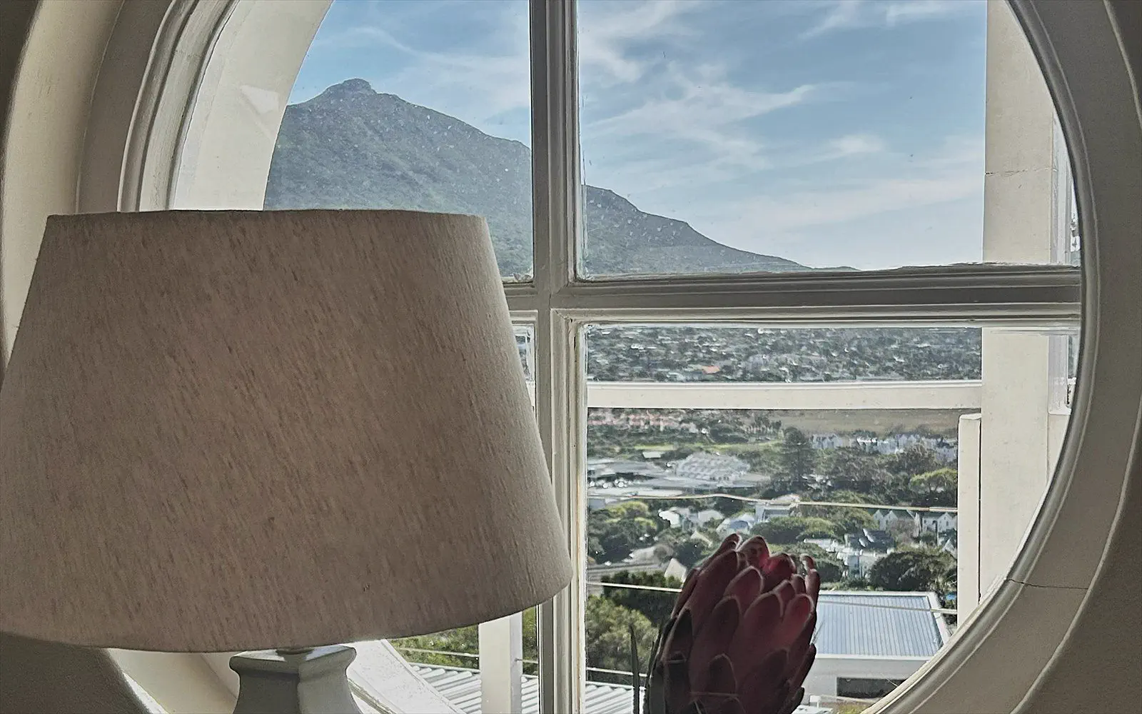 View of the mountains through the characteristic round window, with a lamp and a protea