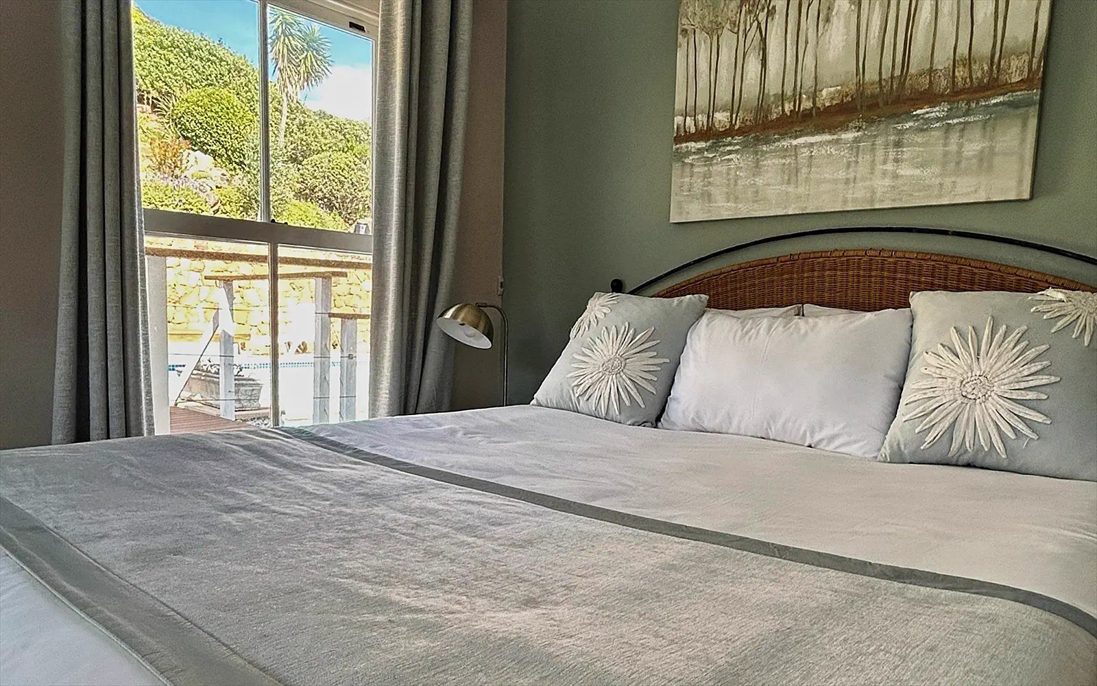 Made bed with a rattan headboard and daylight through the terrace window