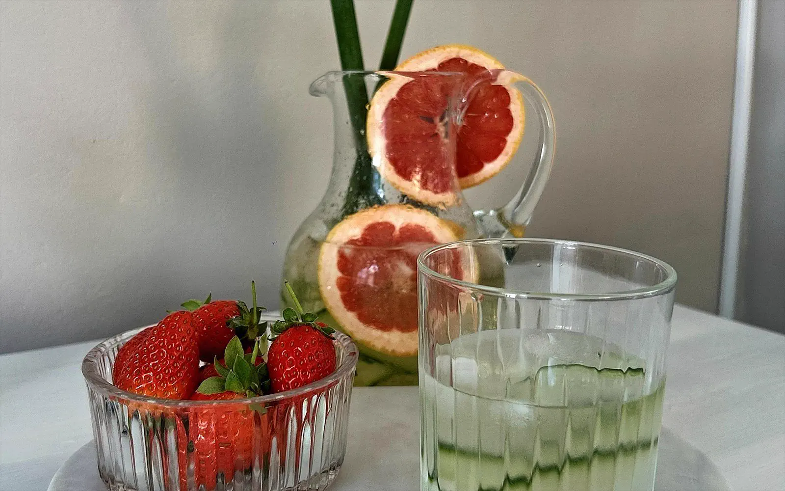 Carafe of infused water, grapefruit and strawberries on a marble top