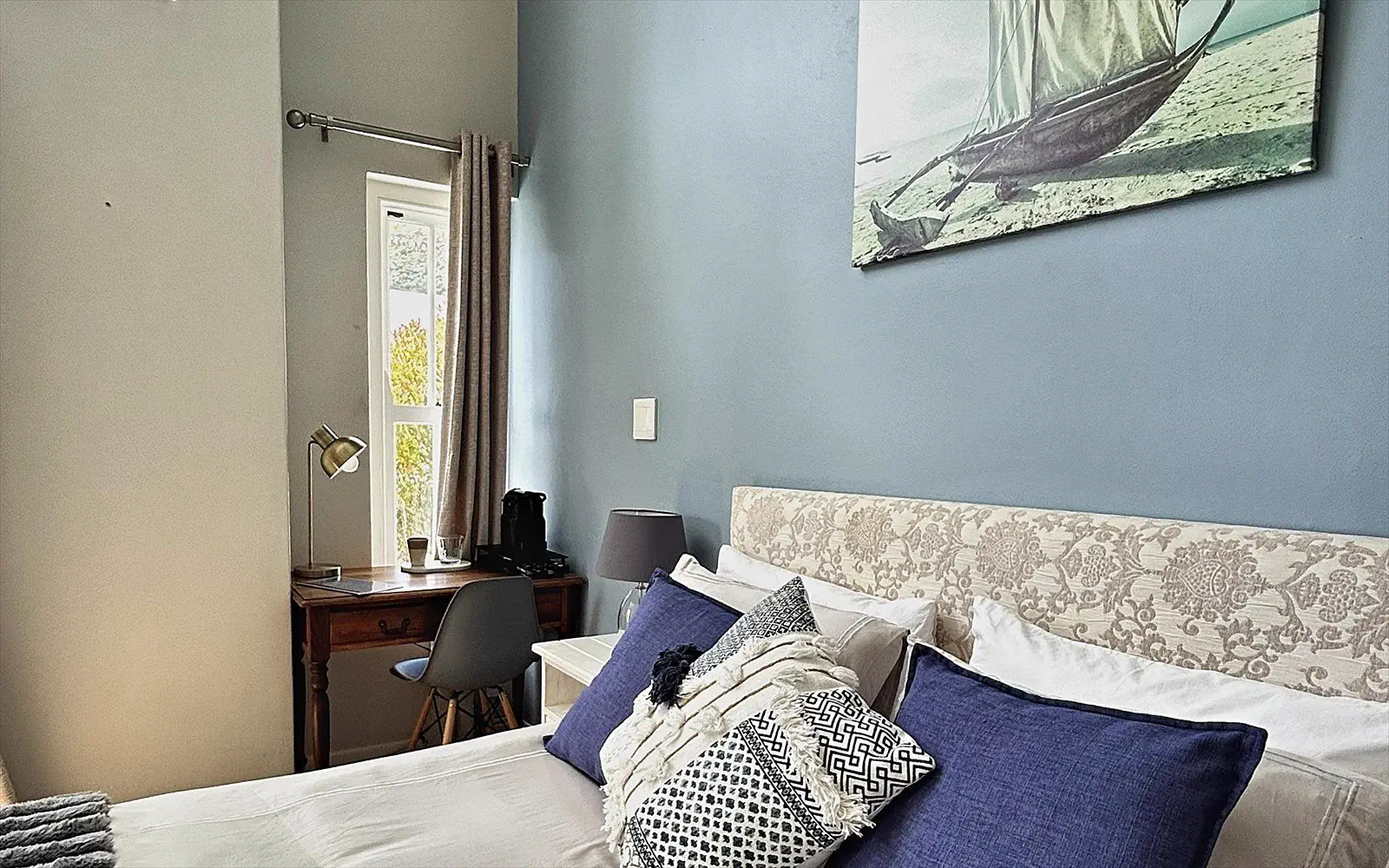 Made bed with fresh linen, cushions and the sailing-boat painting