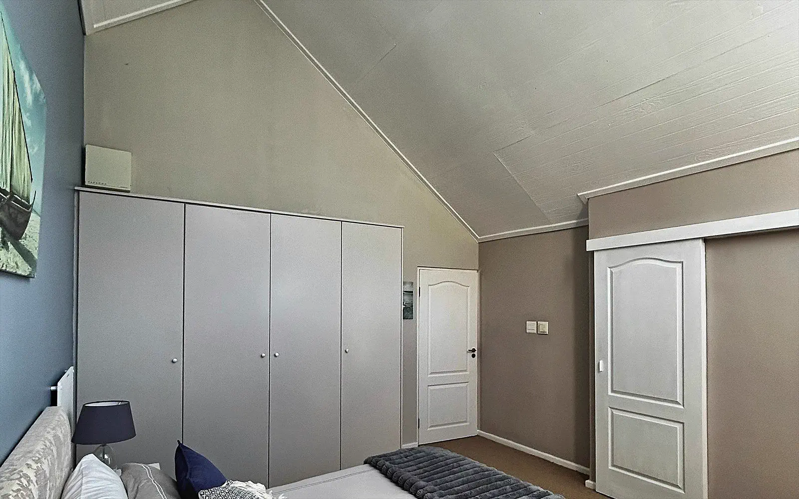 Spacious wall of wardrobes with storage under the sloping ceiling