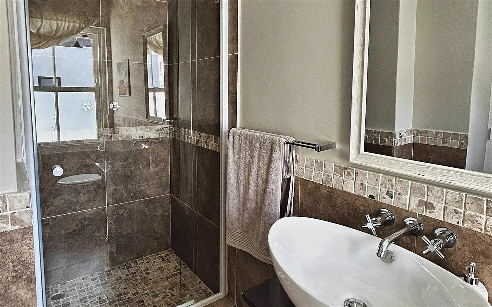 Private bathroom with basin, mirror and a view through to the walk-in shower