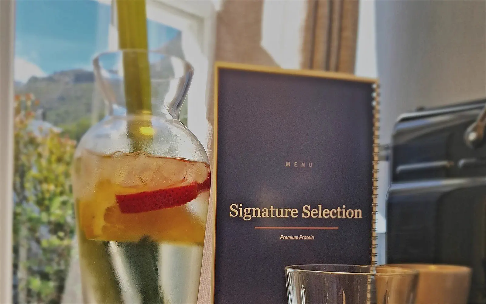 Carafe of infused water, the Signature Selection menu and a glass by the window of The Suite
